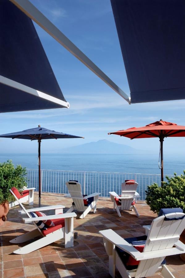 Mediterranean waterfront boutique hotel with floor-to-ceiling windows, coastal chic decor, and stunning views of Bay of Naples at sunset