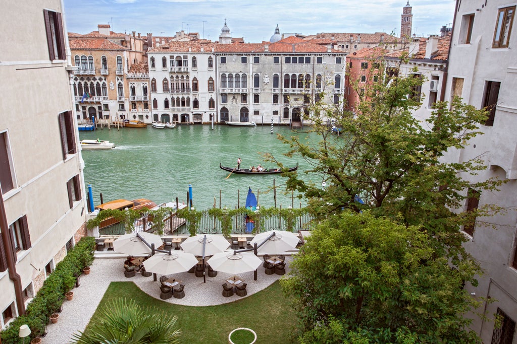 Opulent Venetian palace hotel with ornate Renaissance facade, marble balconies and arched windows overlooking the Grand Canal at sunset