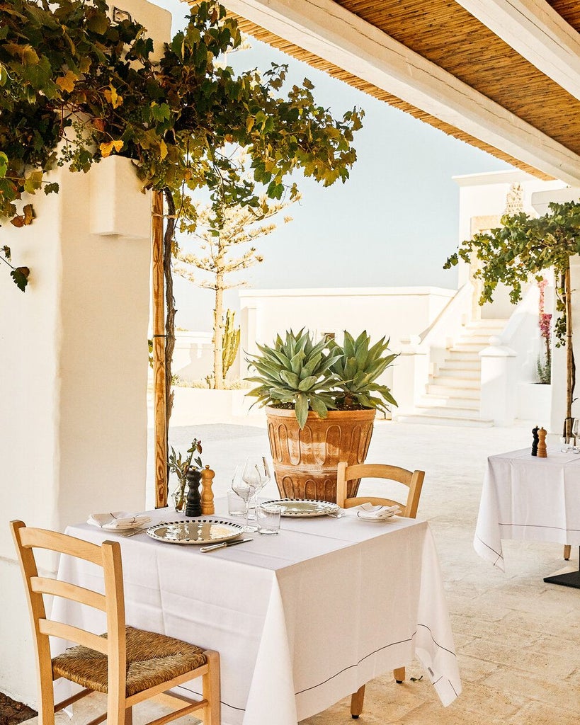 Rustic stone villa nestled in golden Puglian countryside, surrounded by olive groves, with elegant white-washed architecture and traditional Mediterranean charm