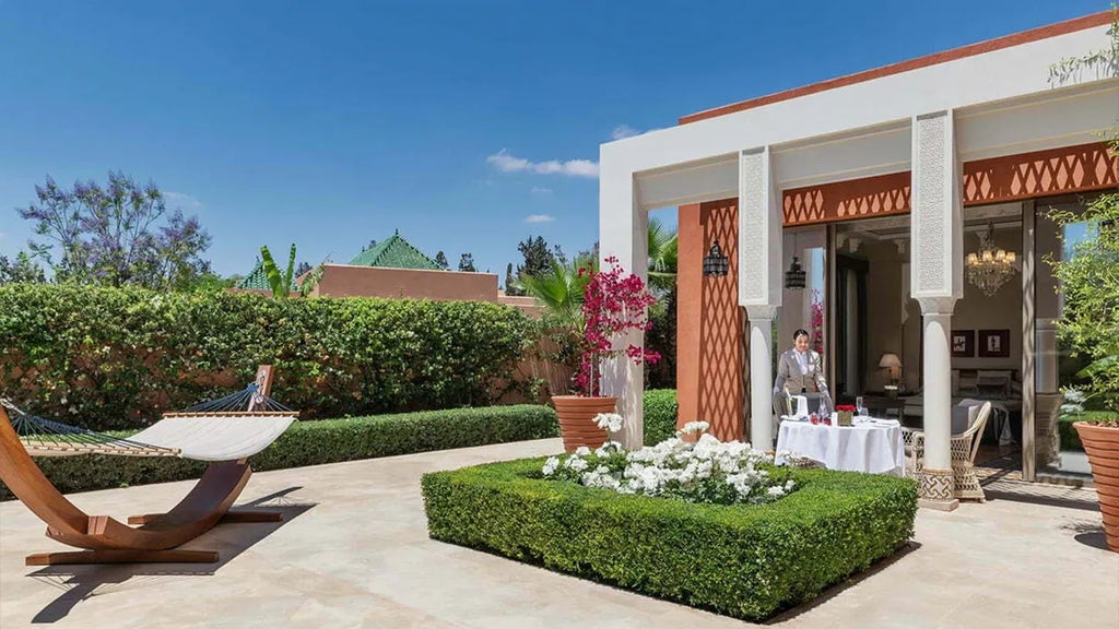 Luxurious Moroccan resort with white architecture, lush green gardens, snow-capped Atlas Mountains in background, reflecting serene elegance of scenset hospitality