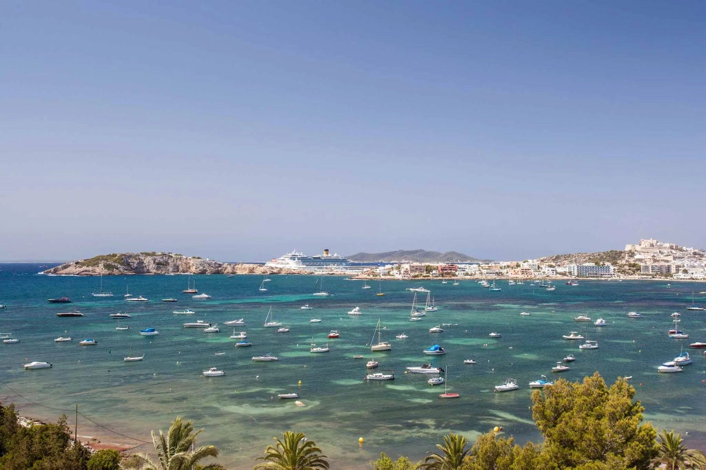 Luxurious white-walled Hotel at Talamanca coastline with modern architecture, blue Mediterranean waters, and palm trees in scenic Spanish landscape