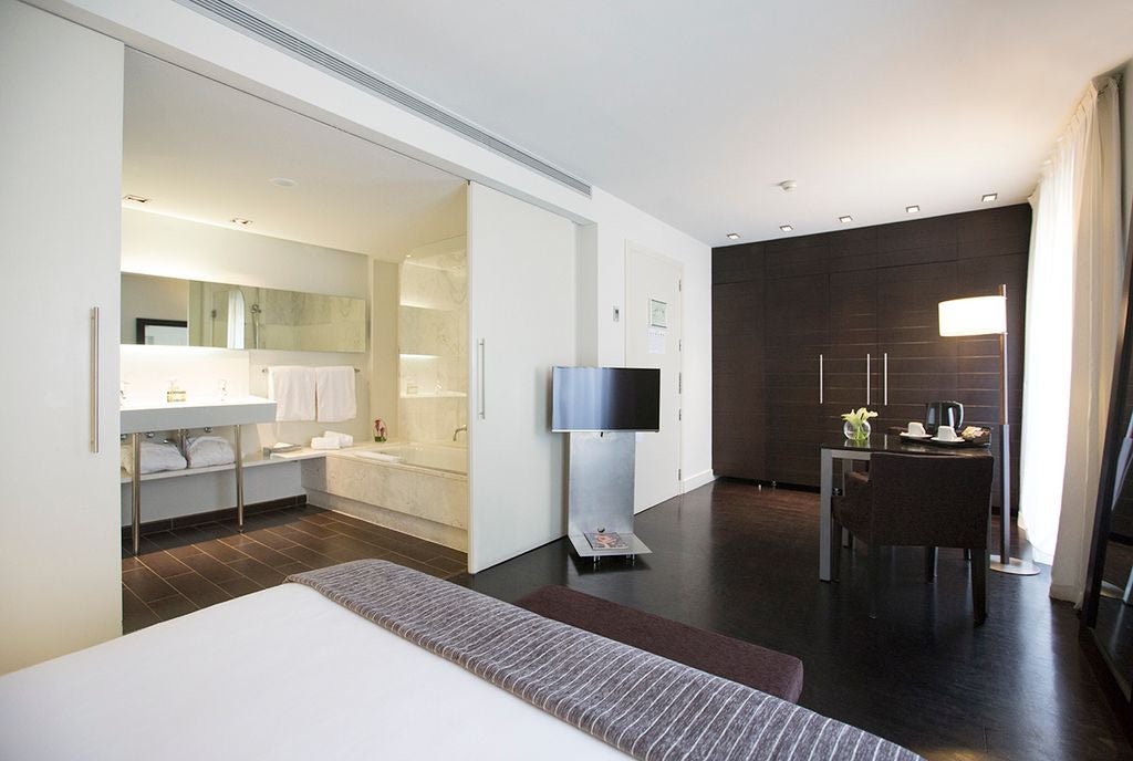 Elegant Spanish hotel room with soft neutral tones, plush white bedding, modern minimalist design, and sophisticated urban luxury decor