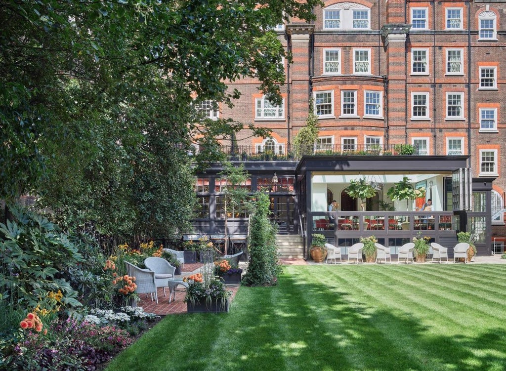 Historic luxury hotel The Goring London featuring elegant white Victorian architecture with red awnings and manicured garden entrance