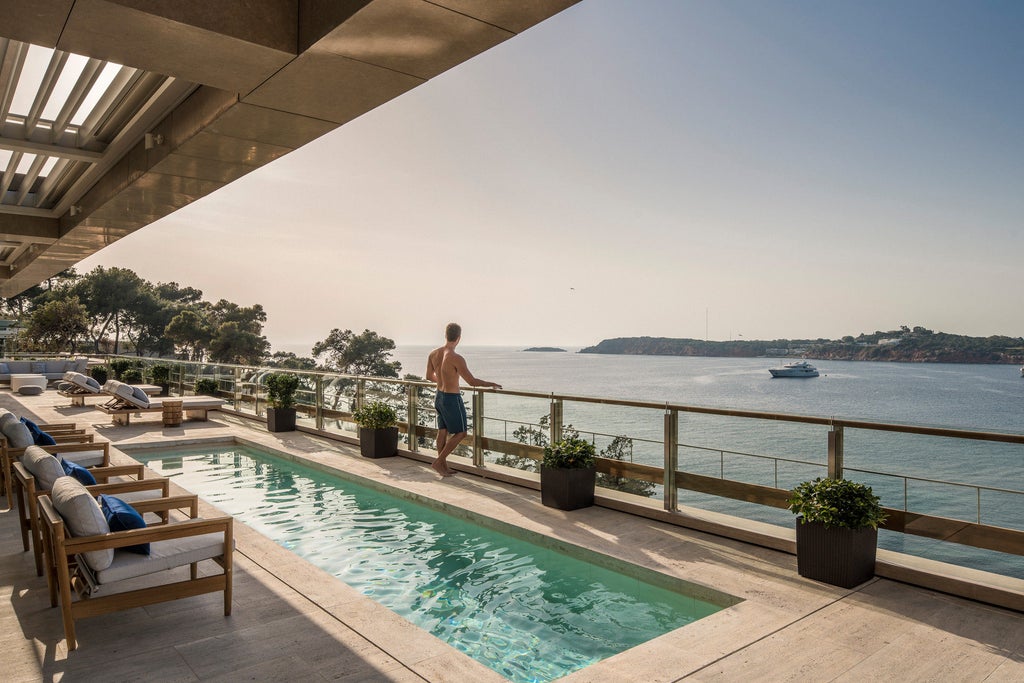 Luxury beachfront hotel in Athens with modern white buildings, infinity pools, and private cabanas overlooking the Aegean Sea at sunset