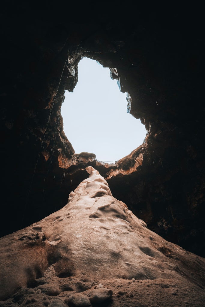 Adventurers exploring vibrant lava tunnels with colorful rock formations, dramatic light streams, and rugged volcanic terrain in scenic Icelandic underground landscape