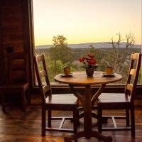 Rustic luxury cabin interior at Scenset Mountain Ranch with wooden furnishings, large windows overlooking scenic landscape, warm natural lighting