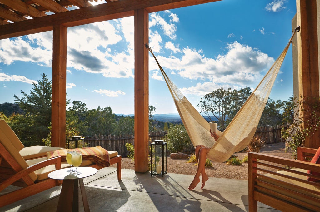 Luxurious Four Seasons Santa Fe resort nestled in desert landscape with adobe-style architecture, mountain backdrop and flowering gardens