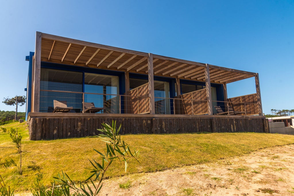 Minimalist bungalow at Bahia Vik resort with sleek wooden design, expansive windows overlooking coastal landscape of José Ignacio, Uruguay