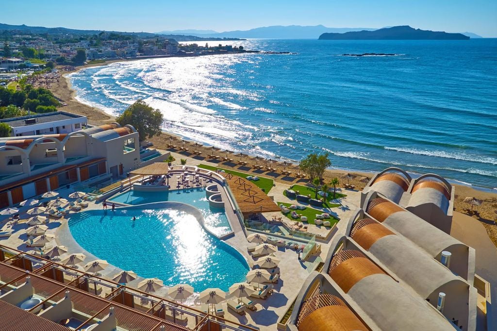 Luxurious beachfront hotel features whitewashed domed architecture, private infinity pools, and ocean views along Crete's coastline