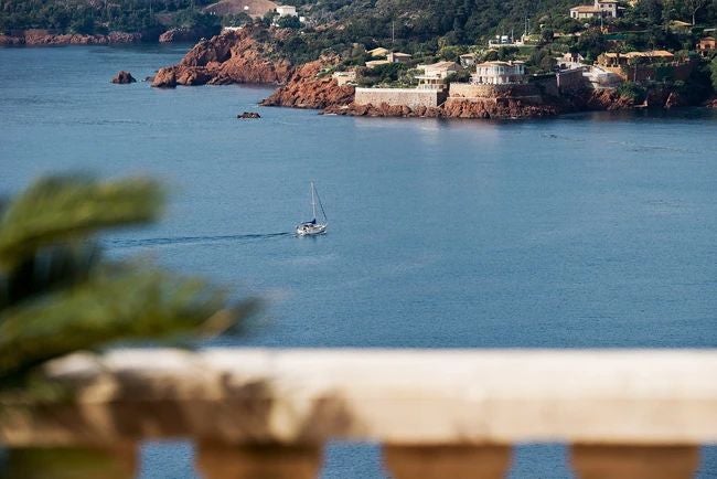 Luxurious coastal hotel nestled on French Riviera cliffs, featuring elegant white architecture, azure Mediterranean Sea, and lush tropical landscaping