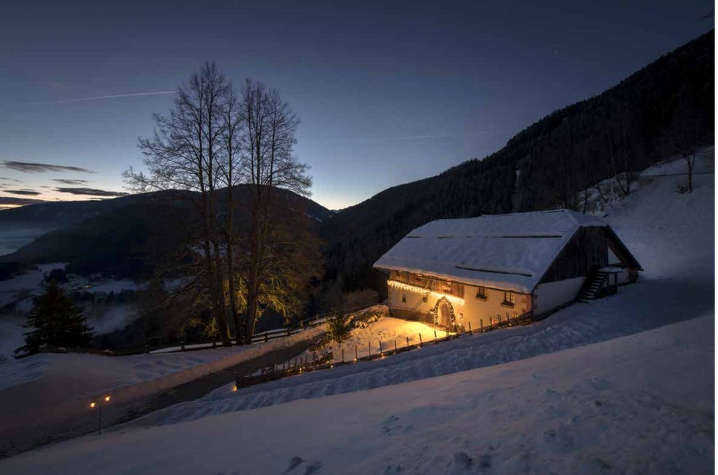 `White Deer Mountain Lodge sits nestled in snowy Italian Alps, featuring modern stone-and-glass architecture with panoramic mountain views`