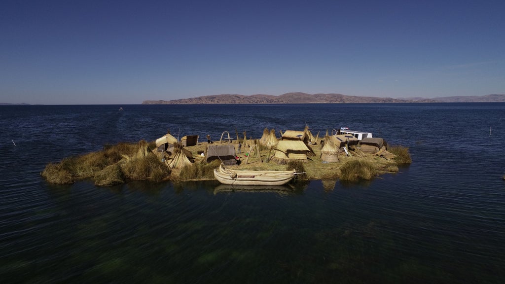 Contemporary luxury lodge with stone facade nestled on Lake Titicaca's shore, featuring floor-to-ceiling windows and scenic water views