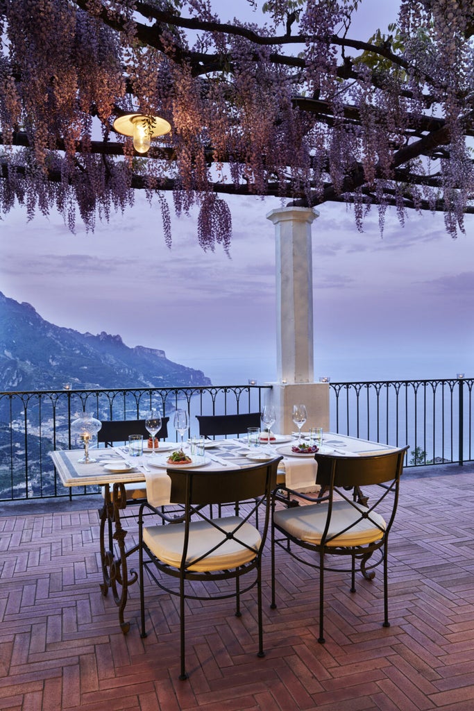 Elegant pink-hued luxury hotel Palazzo Avino perched on Amalfi Coast cliffside, with lush gardens and Mediterranean Sea views