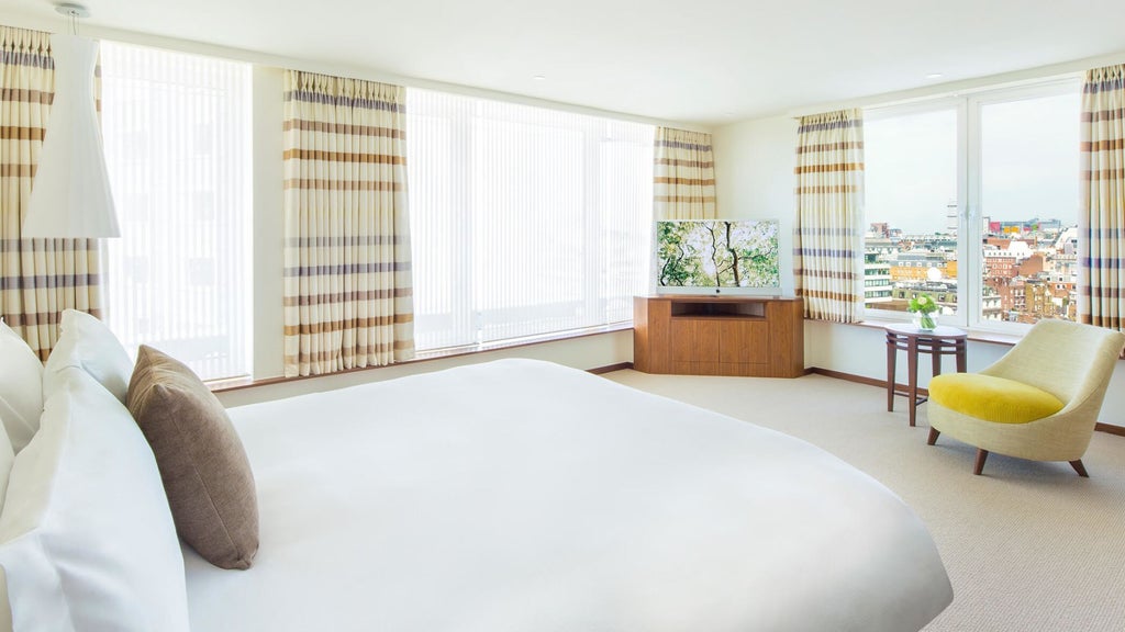 Elegant COMO Suite with plush king bed, modern minimalist decor, large windows overlooking London's cityscape, warm neutral tones, and sophisticated design