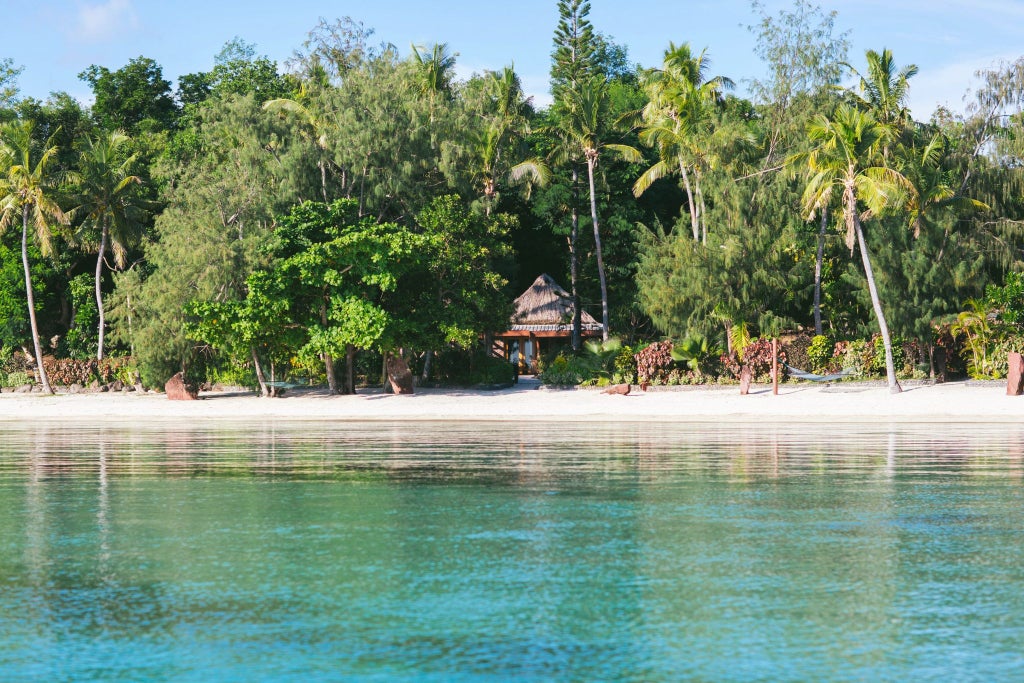 Spacious beachfront villa with panoramic ocean views, teak wood floors, private terrace, and elegant tropical decor in lush Fijian resort setting