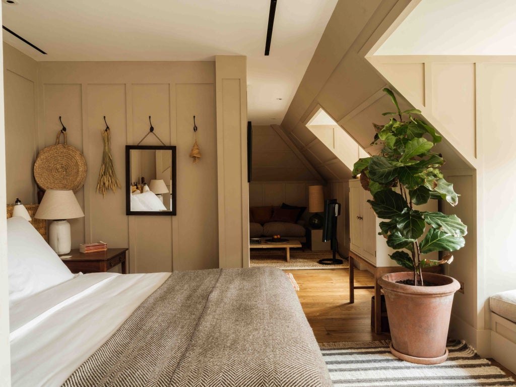 Elegant light-filled bedroom at Heckfield Place with soft neutral tones, minimalist furnishings, floor-to-ceiling windows overlooking lush countryside