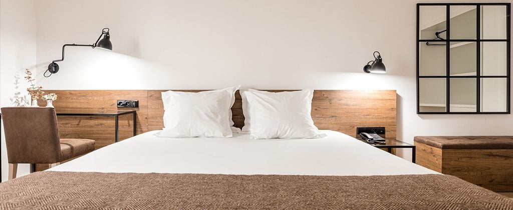 Elegant double room with garden view at Lamego Hotel, featuring modern decor, plush bedding, and warm natural light streaming through large windows in Portugal