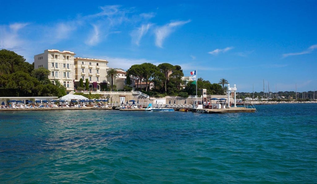 Elegant art deco hotel Belles Rives perched on French Riviera waterfront with private beach, stone balconies and Mediterranean views