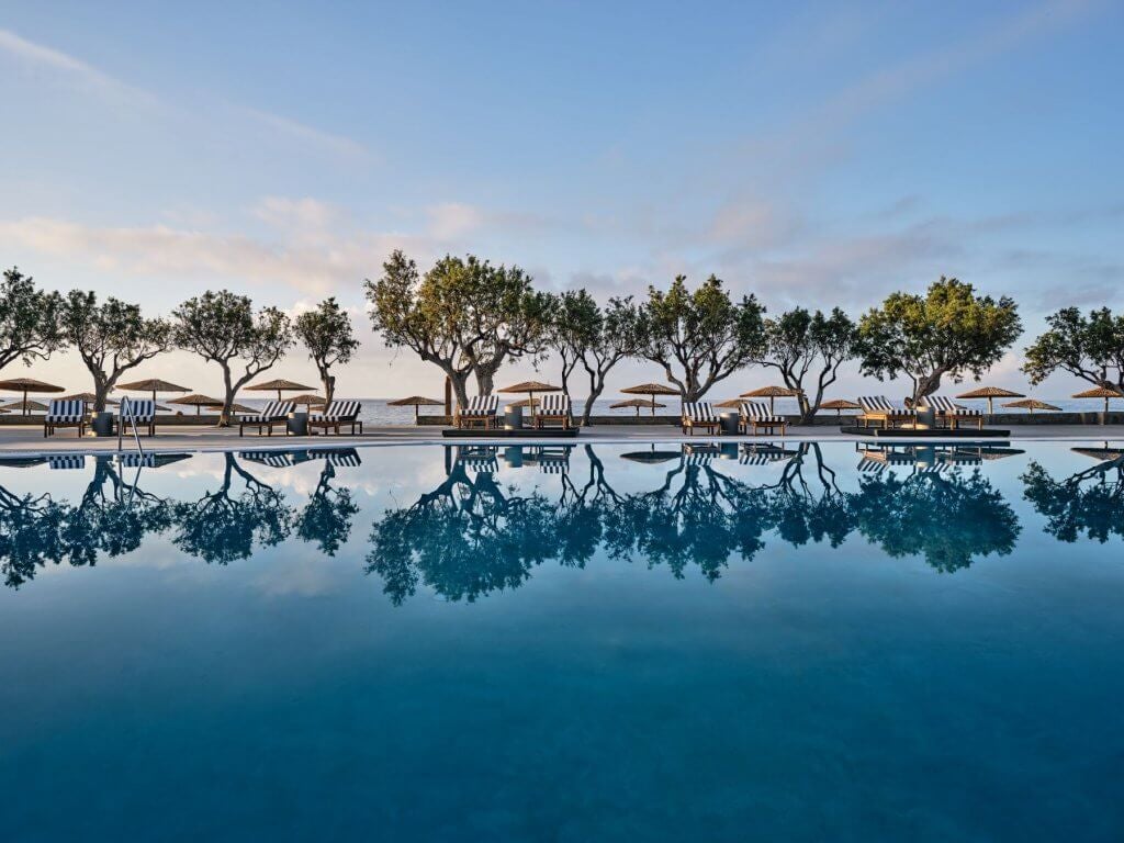 Luxurious modern beachfront resort with minimalist white architecture, azure Aegean waters, and sleek poolside loungers at Scenset Ierapetra Beach Resort