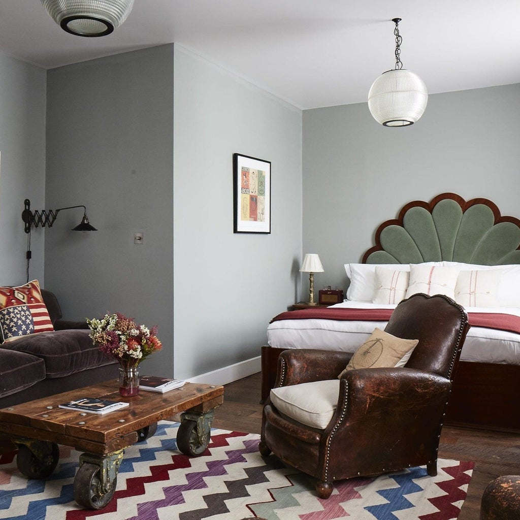 Charming boutique hotel bedroom with eclectic vintage furnishings, exposed brick walls, and artistic decor in a stylish London setting