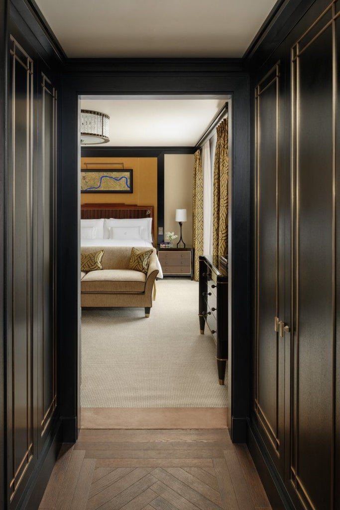 Elegant superior room at a Mayfair luxury hotel with plush ivory bedding, dark wooden furnishings, soft ambient lighting, and refined British interior design