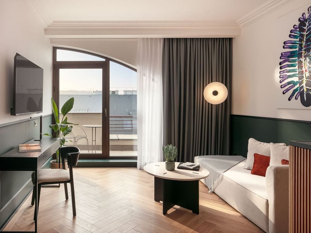 Elegant executive suite in Almanac hotel with modern decor, plush king bed, expansive city view from private balcony overlooking Prague's historic landscape