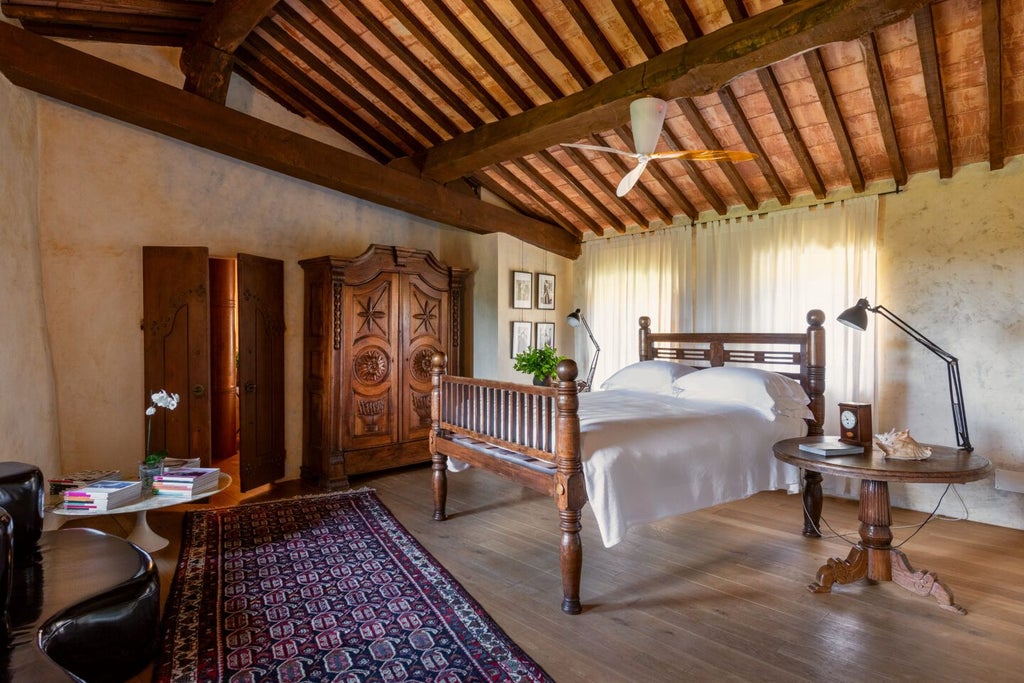 Elegant rustic suite at Castello di Vicarello with stone walls, antique wooden furniture, and panoramic Tuscan countryside views through large windows