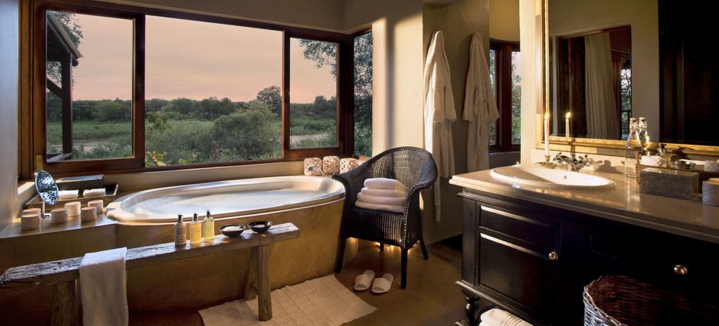 Luxurious riverside safari lodge with elevated wooden deck and infinity pool overlooking the African bush at golden hour