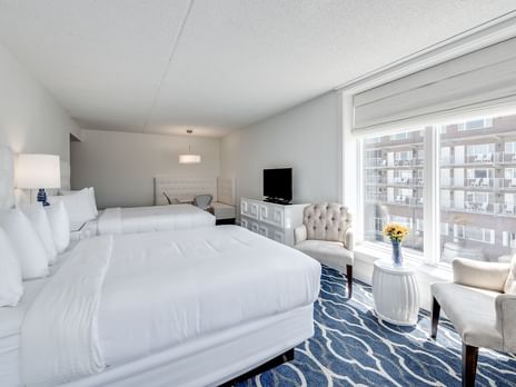 Elegant beachfront hotel with contemporary white exterior, oceanfront balconies, and landscaped palm trees against a bright blue sky