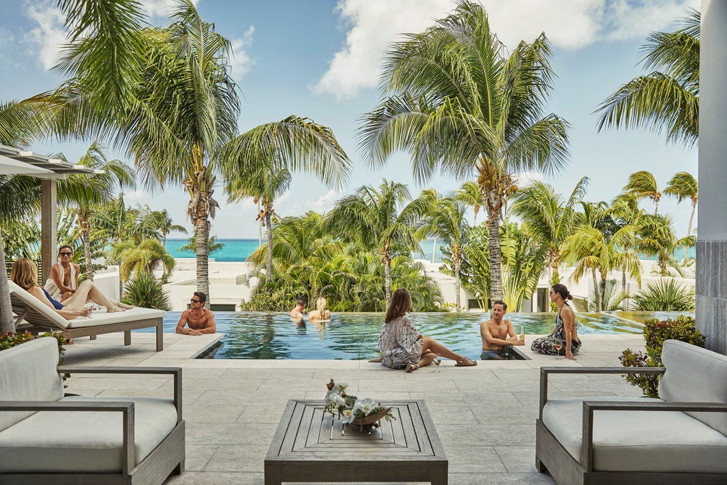 Elegant beachfront resort with white modern buildings, infinity pools overlooking turquoise Caribbean waters and swaying palm trees