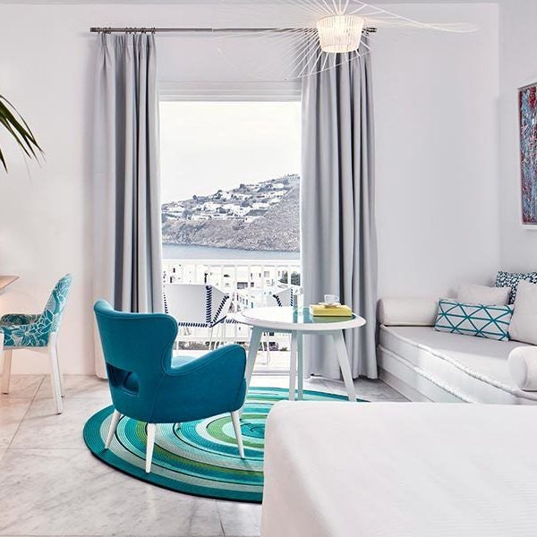 Luxurious Thalassa Suite at Myconian Ambassador Hotel, featuring minimalist white decor, sea view balcony, and elegant modern Mediterranean design in Mykonos, Greece