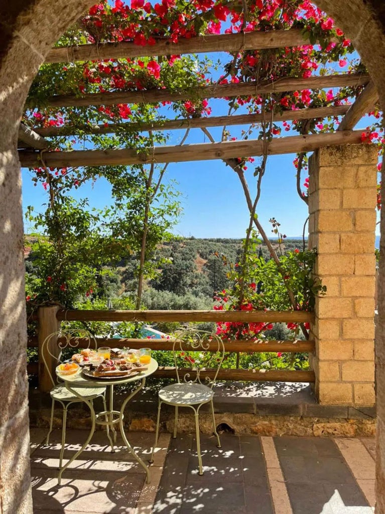 Historic stone mansion-turned-luxury hotel with arched windows and vine-covered walls overlooking the Mediterranean Sea and rolling hills