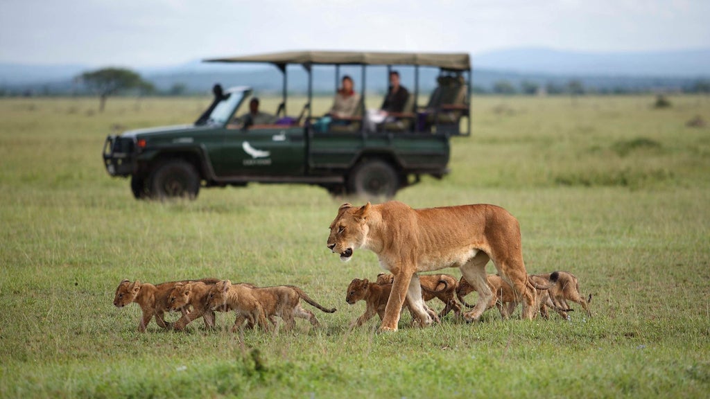 Elegant safari lodge with infinity pool overlooking Serengeti savanna, featuring thatched-roof suites and natural stone accents