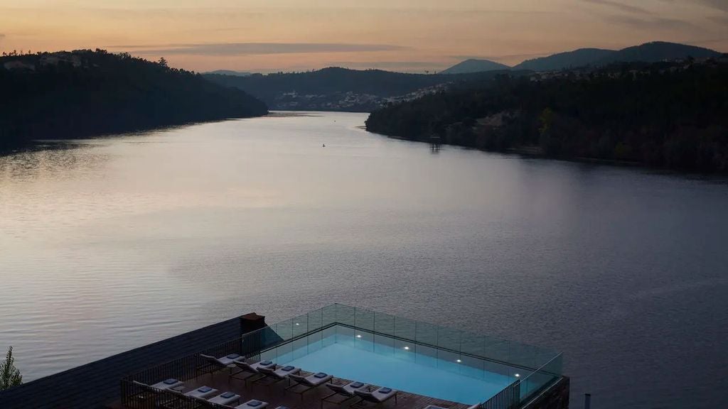 Elegant infinity pool overlooking the Douro Valley vineyards, featuring glass barriers and luxurious loungers against mountain vistas