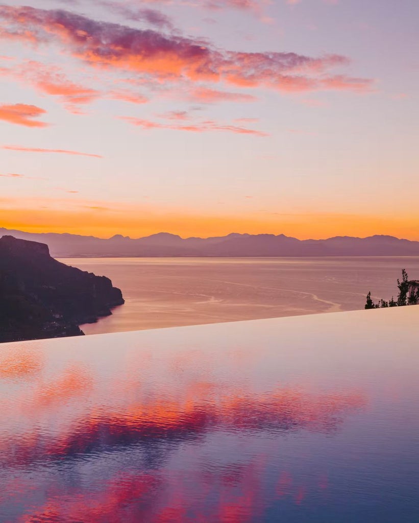 Elegant infinity pool overlooking Amalfi Coast cliffs, with panoramic views of the Mediterranean Sea and lush Italian hillside terraces