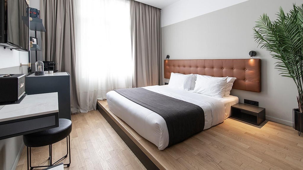 Minimalist medium hotel room with neutral tones, sleek wooden furniture, large window, and city view in The Modernist Thessaloniki, Greece