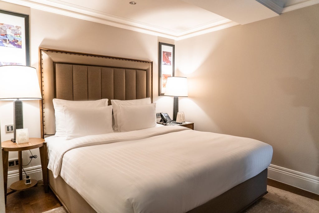 Luxurious duplex hotel room with elegant wooden floors, modern furnishings, and expansive windows overlooking Istanbul's historic cityscape at sunset