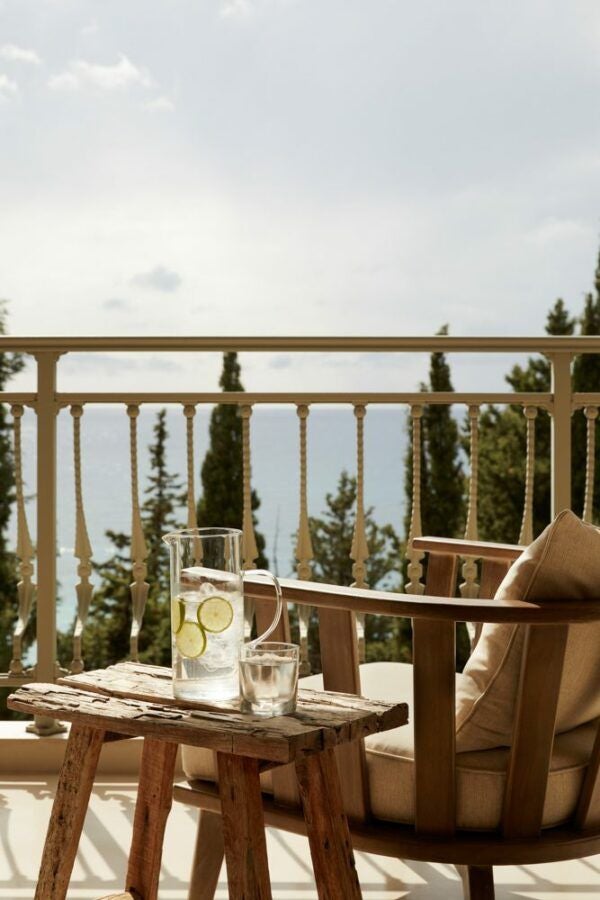 Minimalist Greek luxury retreat with pristine white walls, elegant wooden furniture, and expansive sea view from private balcony in Kefalonia