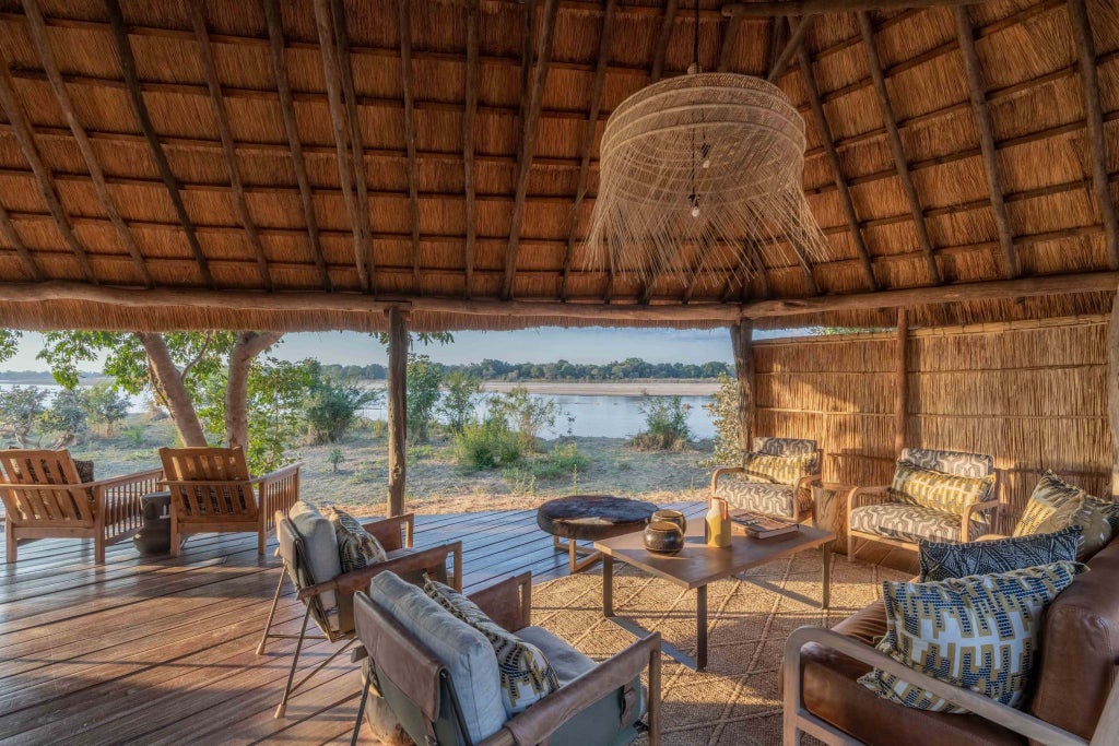 Luxurious safari tent overlooking the scenic Zambian wilderness, blending canvas elegance with natural teak wood elements and panoramic river views at Time + Tide Kakuli Camp.