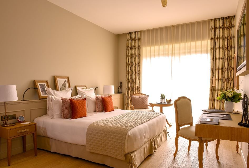 Elegant deluxe hotel room with soft neutral tones, luxurious king bed, modern French design, and plush furnishings at Chais Monnet & Spa in Cognac, France