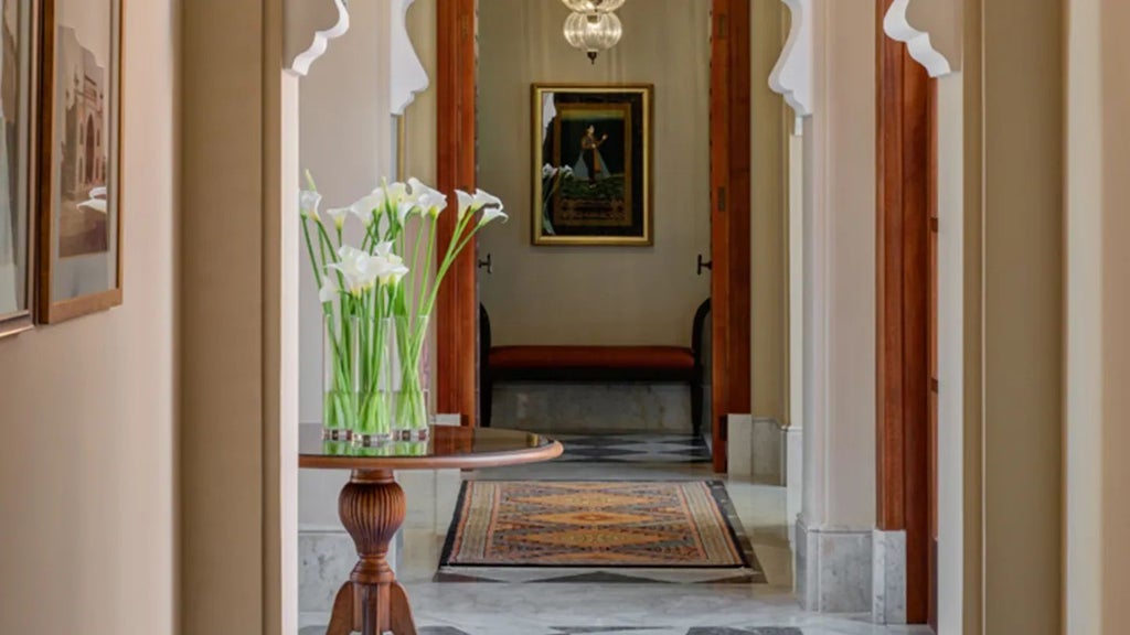 Luxurious Moroccan resort with palm-lined courtyard, traditional architecture, reflecting pool, and snow-capped Atlas Mountains in background