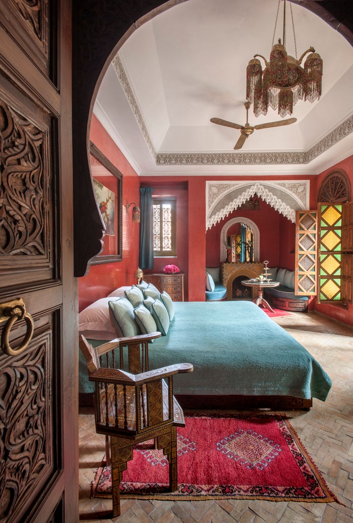 Opulent Moroccan courtyard with ornate archways, marble fountain, and lush greenery at La Sultana hotel under blue Marrakech sky