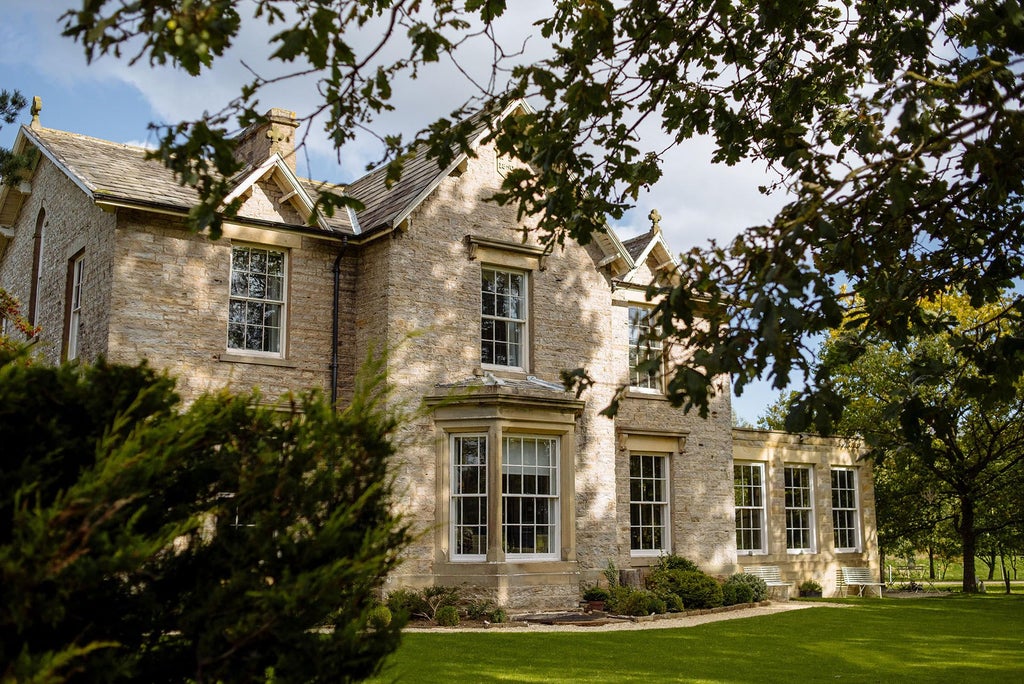 Luxurious countryside boutique hotel with stone exterior, nestled in rolling Yorkshire landscape, featuring elegant architecture and inviting entrance