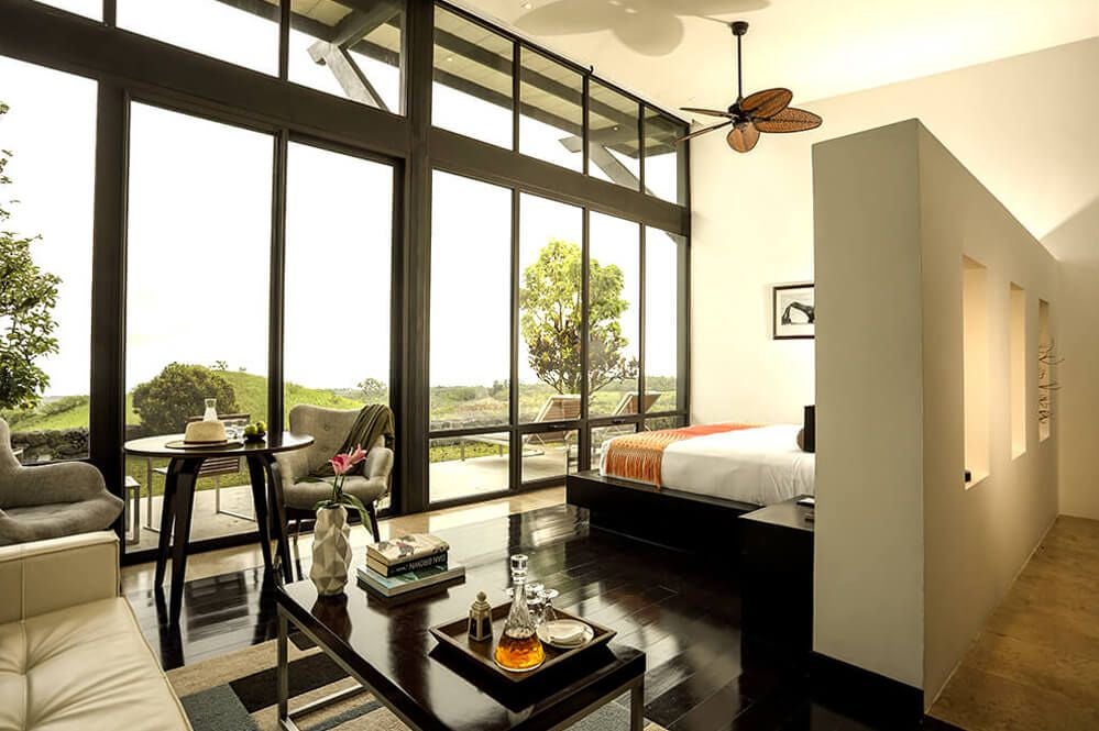 Spacious Pikaia Lodge Garden Suite with panoramic view, elegant contemporary design, natural textures, and lush Ecuadorian landscape through expansive windows