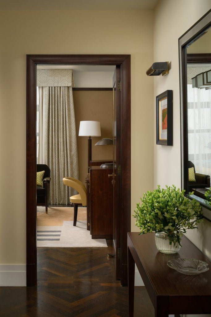 Elegant classic suite with plush king bed, cream marble bathroom, and refined neutral tones at a luxury Mayfair hotel in central London