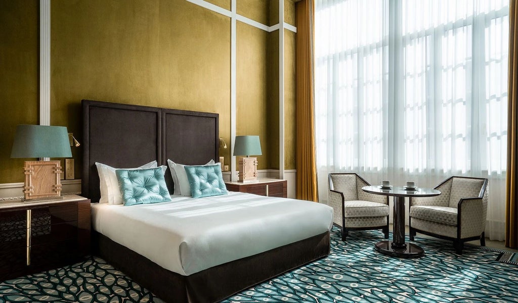 Elegant executive hotel room at Monumental Palace with panoramic city views, refined furnishings, plush king bed, and sophisticated neutral color palette in Porto