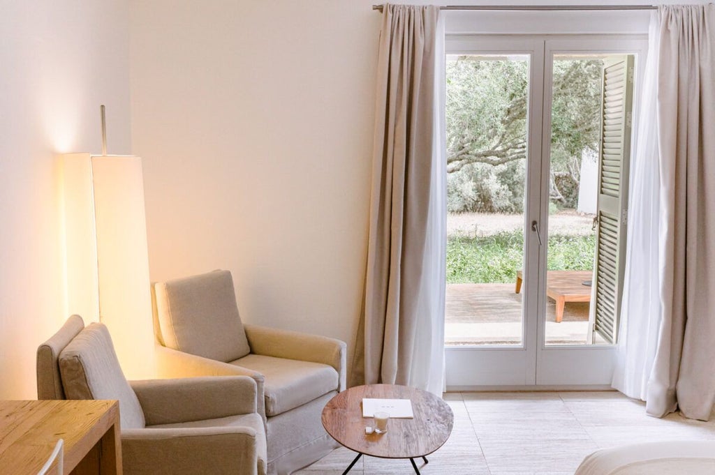 Elegant white-washed luxury hotel room with minimalist design, featuring crisp linens, stone floors, and panoramic view of Spanish countryside landscape