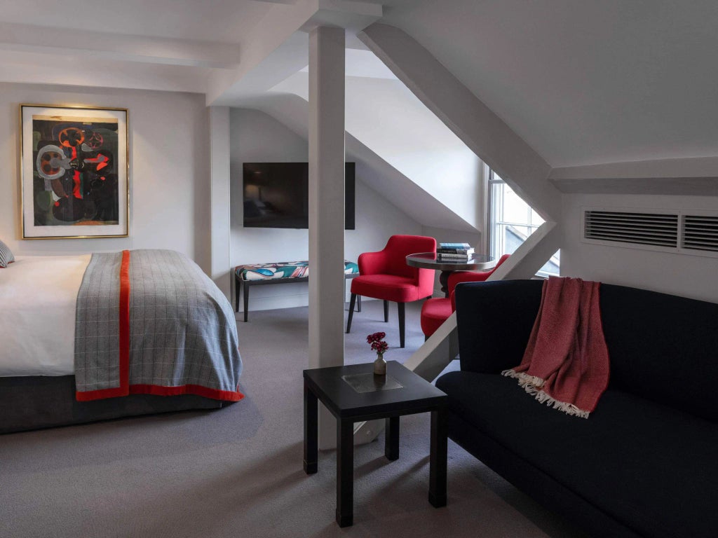 Elegant vintage bedroom with rich mahogany furnishings, crisp white linens, and ornate period details in classic United Kingdom boutique hotel room