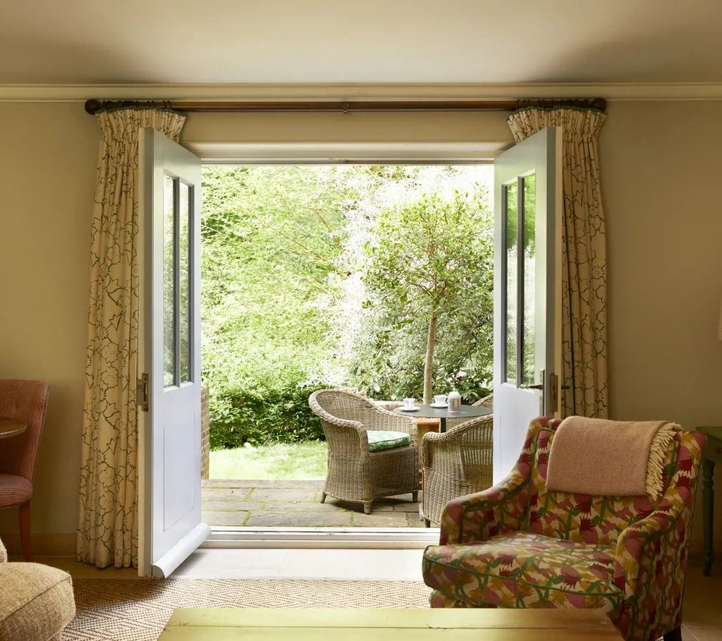 Luxurious forest-themed hotel suite with natural wood paneling, plush green furnishings, and expansive windows overlooking lush woodland scenery in the United Kingdom.