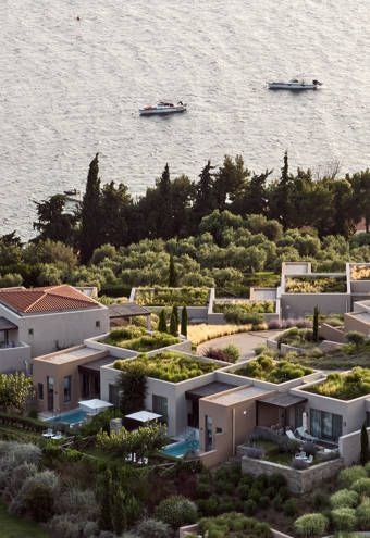 Luxury beachfront resort with white and blue architecture, crystal-clear Aegean waters, private balconies overlooking turquoise sea at scenic Greek coastline